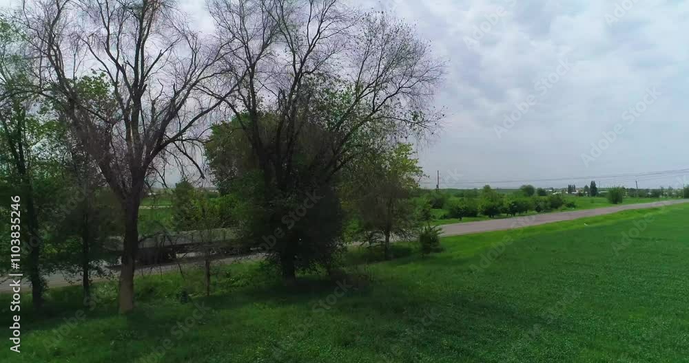 The drone flies on a country road with a truck on it. There are green fields and trees around. The drone flies on a country road with a truck on it. There are green fields and trees around.