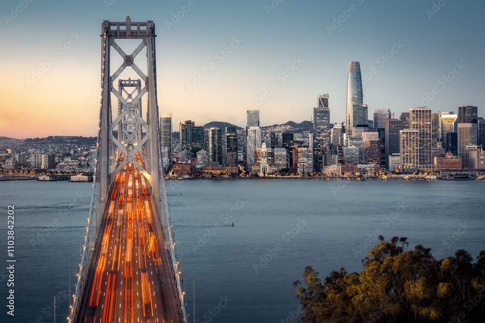 the oakland bay bridge and the skyline of san franciso during sunrise