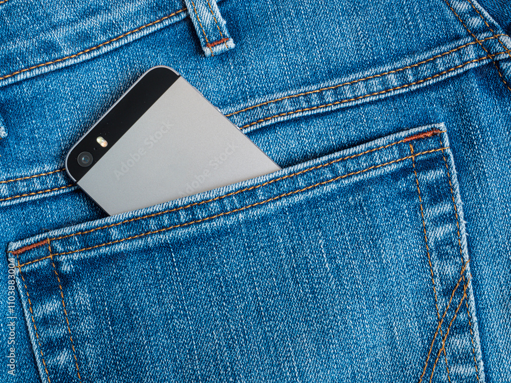 Grey mobile phone with a camera in the back pocket of blue jeans Grey mobile phone with a camera in the back pocket of blue jeans