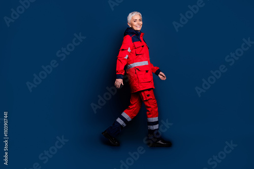 Full size photo of attractive mature lady profile walking wear uniform paramedic doc insurance assistance isolated on dark blue background