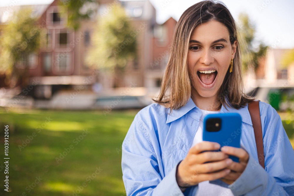 Blonde short hair woman browsing internet with cellphone mobile phone wearing casual clothes shirt gesturing like winner. Smiling open mouth woman look happy, celebrating win, triumph, success, wow. Blonde short hair woman browsing internet with cellphone mobile phone wearing casual clothes shirt gesturing like winner. Smiling open mouth woman look happy, celebrating win, triumph, success, wow.