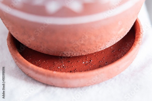 A terracotta flower pot and matching saucer, featuring a white 8-pointed star pattern along the pot’s rim, showcasing the complete set