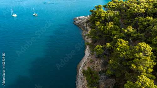 Aerial view of a hill on the Mediterranean Sea. There are boats on the surface of the crystal clear blue water. photo