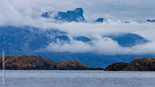 Overcast Summer Day. Panoramic view of islets in the fjord with high mountains shrouded in clouds in the background. Lofoten Islands, Northern Norway. photo