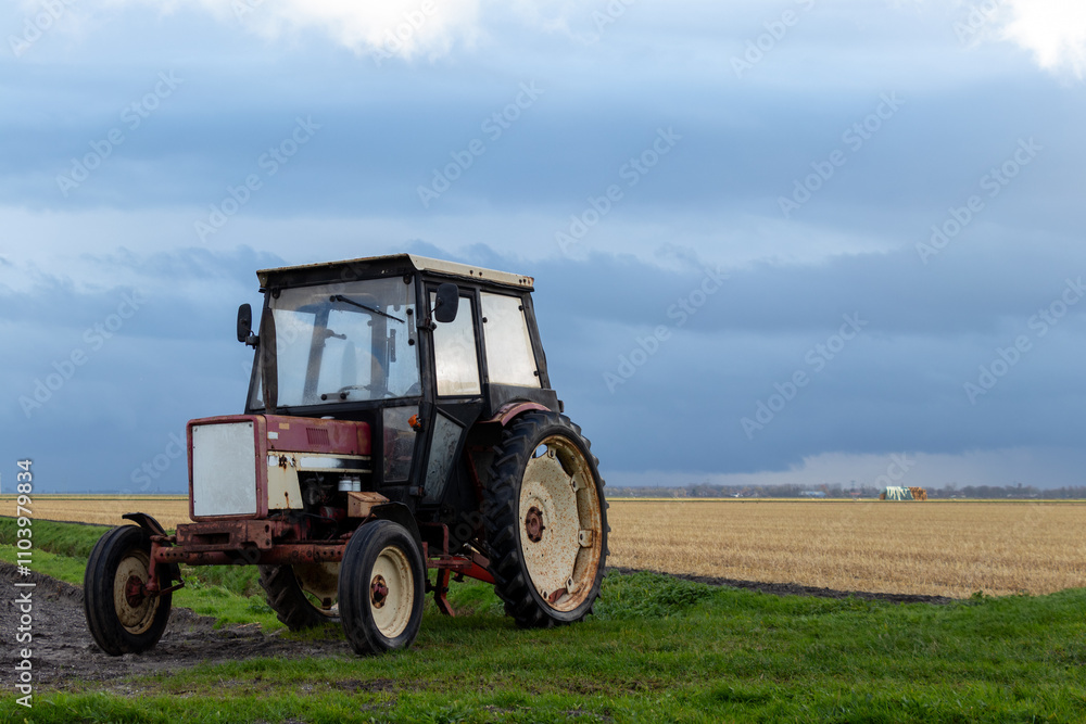 A weathered tractor sits on a muddy patch in a vast rural landscape under a dramatic cloudy sky, highlighting agricultural life, vintage machinery, and countryside serenity. A weathered tractor sits on a muddy patch in a vast rural landscape under a dramatic cloudy sky, highlighting agricultural life, vintage machinery, and countryside serenity.