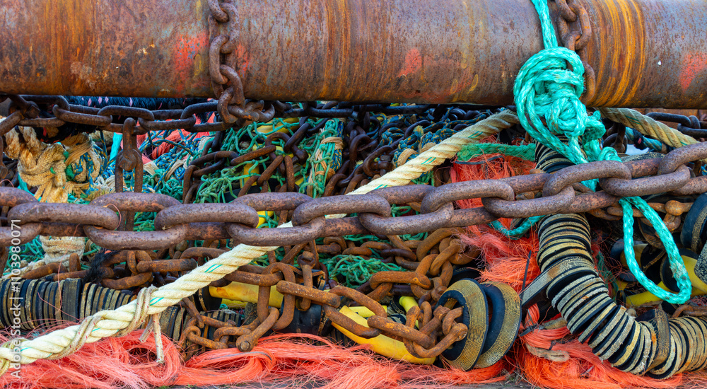 A close-up of fishing equipment with rusted chains, ropes, and colorful nets, showcasing the textures and details of maritime tools in a vibrant, rugged composition. A close-up of fishing equipment with rusted chains, ropes, and colorful nets, showcasing the textures and details of maritime tools in a vibrant, rugged composition.