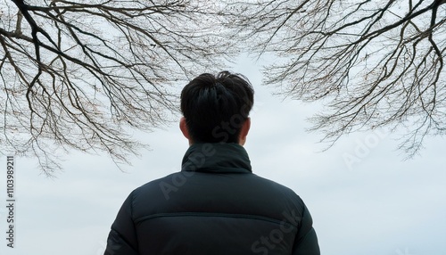 겨울철 나뭇잎이 없는 가지 아래 혼자 서 있는 사람의 실루엣