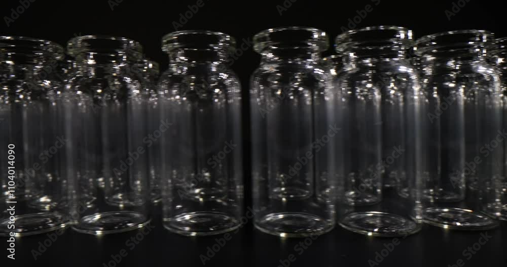 Row of transparent glass jars for cosmetic products on black background. Specialized glassware for storing liquid creams and beauty oils Row of transparent glass jars for cosmetic products on black background. Specialized glassware for storing liquid creams and beauty oils