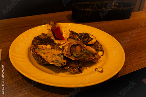 This is a plate of oysters. The dish is sitting out in a restaurant for patrons to eat. The shells of these bivalve mollusks are in a beautiful presentation to make them look more appetizing. photo