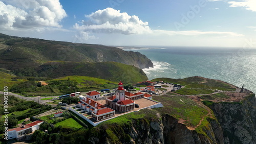 4k aerial view of dangerous cliff and Cape Roca lighthouse Cabo da Roca red and white lighthouse at Europe western edge. Portugal