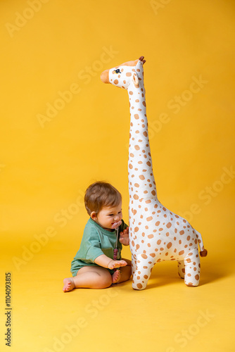 Photography Cute little baby child girl playing with a stuffed giraffe toy sitting on a yellow background with copy space