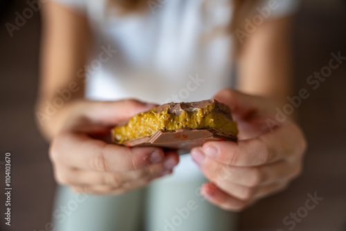 Dubai chocolate with pistachio paste and kataifi dough in hands of little girl. Confectionery handmade sweets at home in the kitchen.  photo