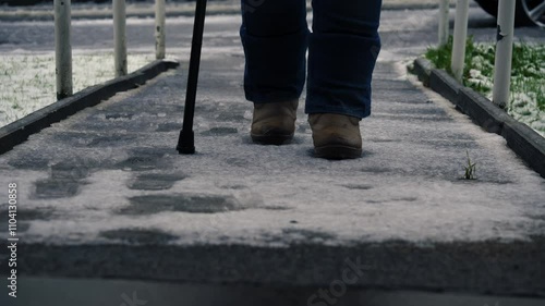 Woman with walking stick on slippery path in snow winter weather 