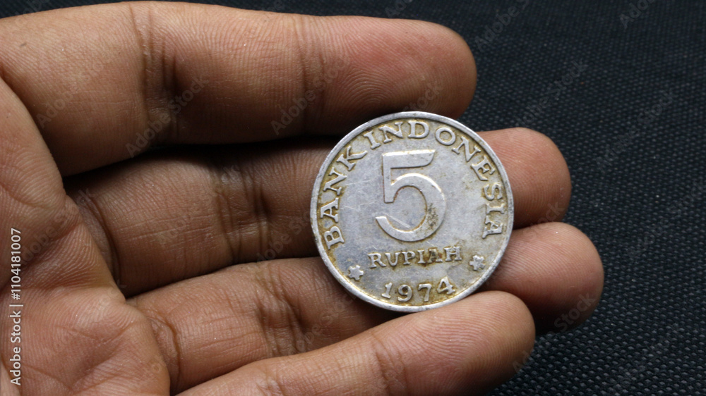 Hand holding an old five rupiah coin Hand holding an old five rupiah coin