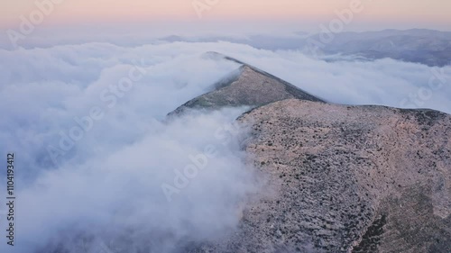 Cinematic drone journey over epic mountain landscapes at sunset, where dense fog and rolling clouds create a tranquil and mysterious atmosphere.