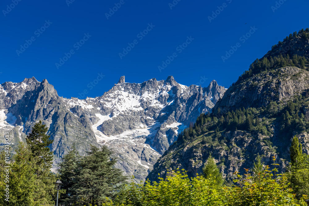 Val Ferret mountain landscape in the Alps. Tour du Mont Blanc beautiful scenic view from the hiking path on the way from Itlay to Switzerland. Alpine meadow and high snow peaks of the Alps on the sun Val Ferret mountain landscape in the Alps. Tour du Mont Blanc beautiful scenic view from the hiking path on the way from Itlay to Switzerland. Alpine meadow and high snow peaks of the Alps on the sun