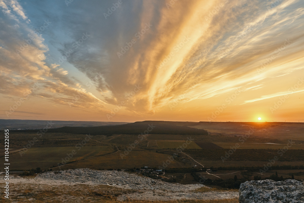 Scenic sunset landscape with clouds and grassy hills in the countryside for travel and nature concepts
