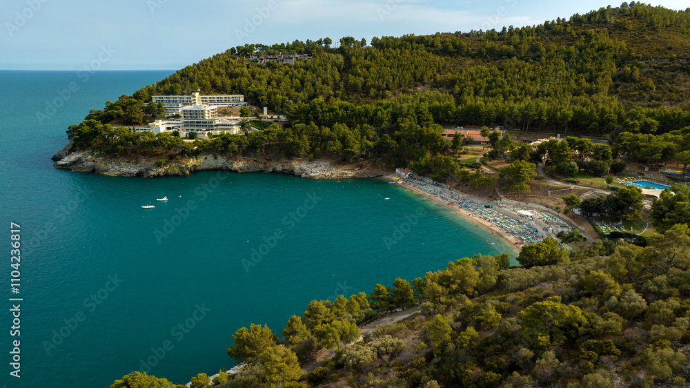 Fototapeta premium Aerial view of a bay with a small beach surrounded by hills with trees and forest.