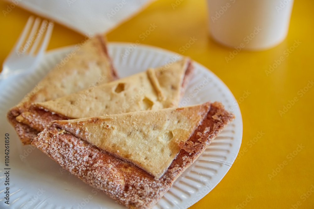 Freshly baked tortilla chips with sugar and cinnamon on a paper plate next to a glass, fork, and napkins against a yellow background, close-up. Freshly baked tortilla chips with sugar and cinnamon on a paper plate next to a glass, fork, and napkins against a yellow background, close-up.