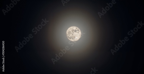 Bright full moon surrounded by a halo in a dark sky representing celestial phenomenon
 photo