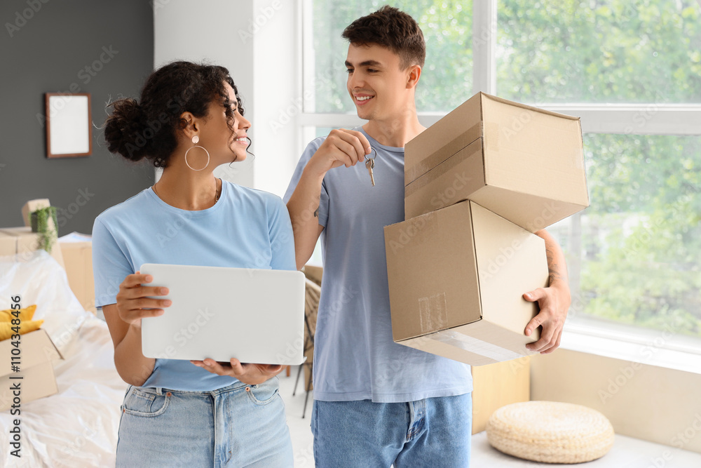 Young couple with laptop and boxes in room on moving day Young couple with laptop and boxes in room on moving day