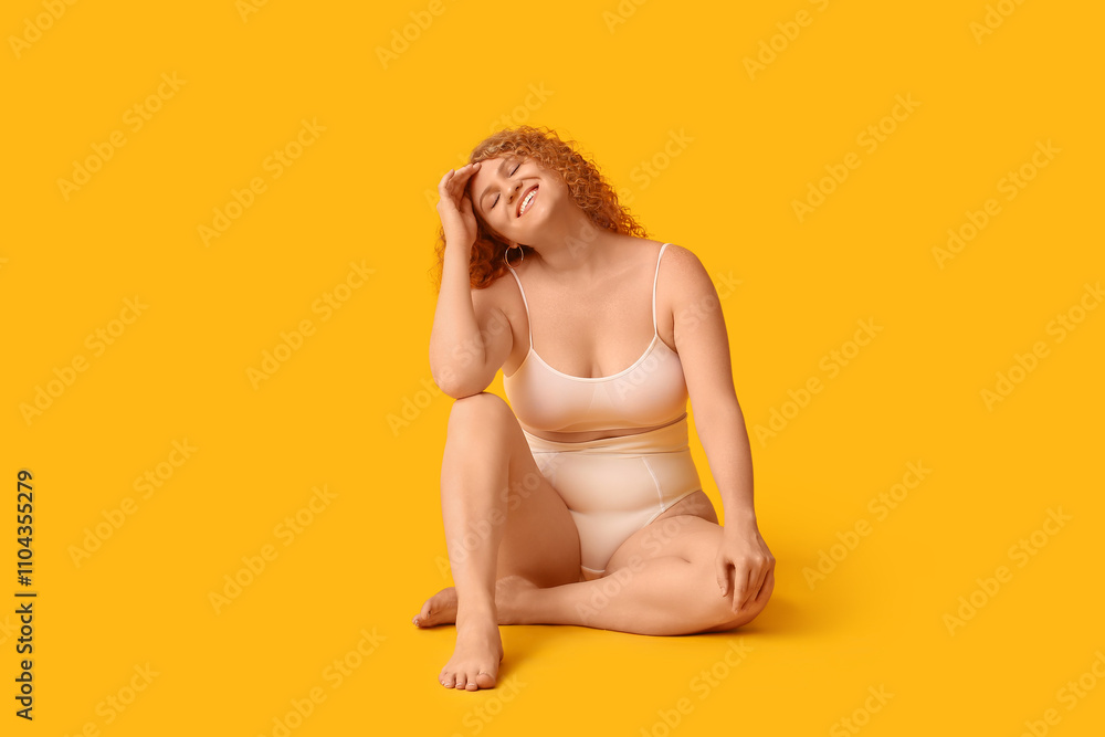 Beautiful young happy body positive woman in trendy underwear sitting on yellow background Beautiful young happy body positive woman in trendy underwear sitting on yellow background