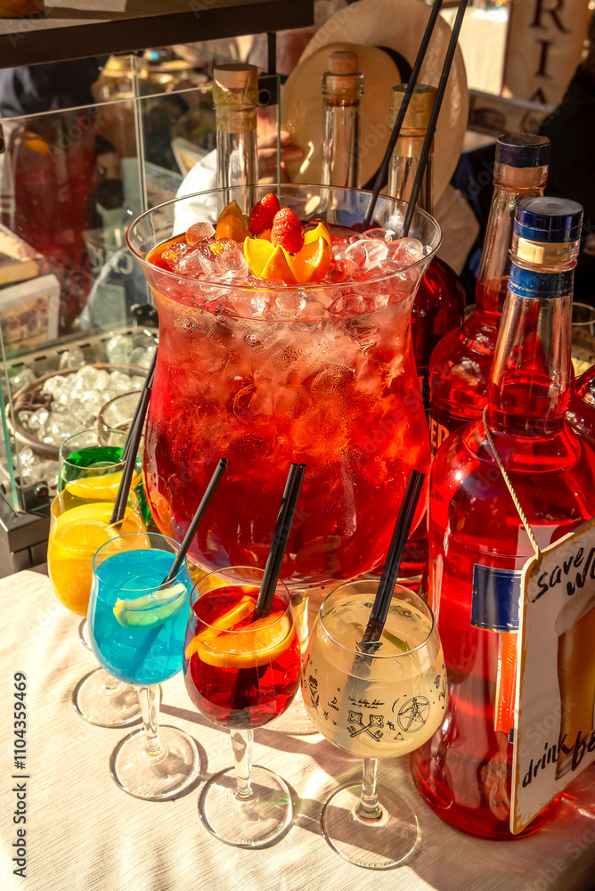 Street trade. Large glass vessel with sangria with ice and colorful cocktails in glasses on the counter