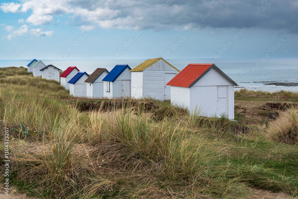 White beach huts with colourful roofs at Gouville-sur-Mer in Normandy, France White beach huts with colourful roofs at Gouville-sur-Mer in Normandy, France