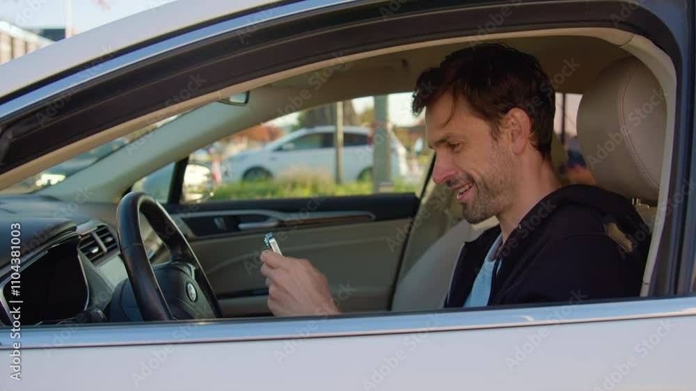 Man sits in car-sharing vehicle playing game on smartphone Man sits in car-sharing vehicle playing game on smartphone