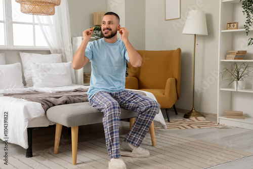 Young man with earplugs sit...