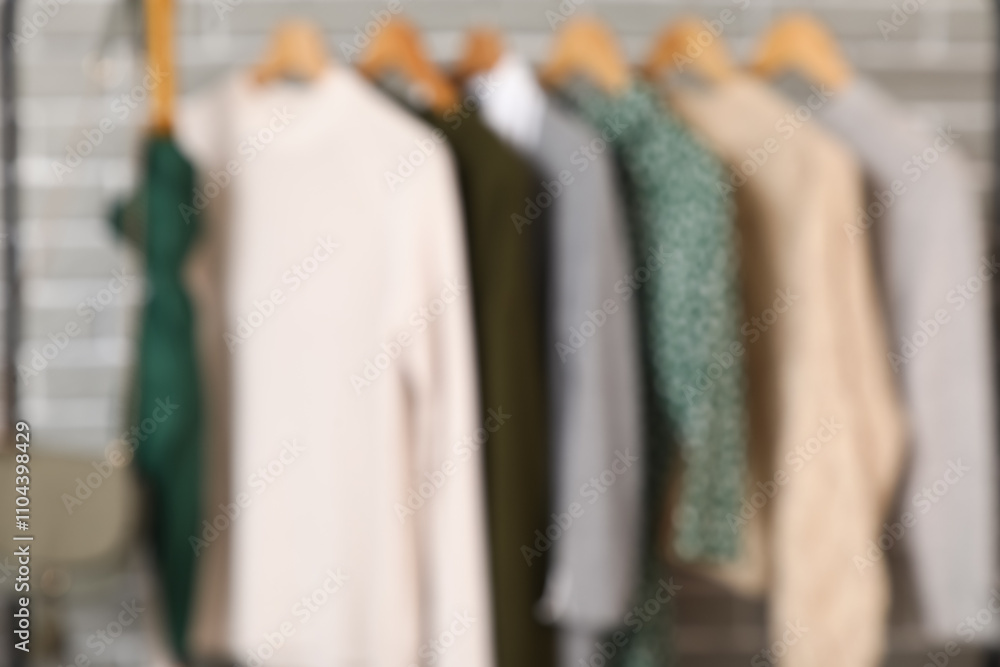 Rack with clothes near grey brick wall in room. Blurred view Rack with clothes near grey brick wall in room. Blurred view