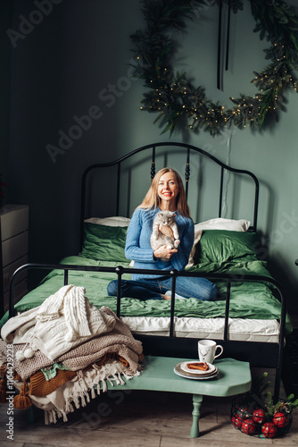 A beautiful woman at home near the Christmas tree with her beloved pet cat