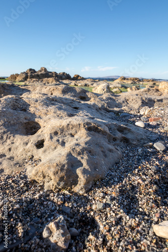 Close up of a boulder on a beach with pebbles