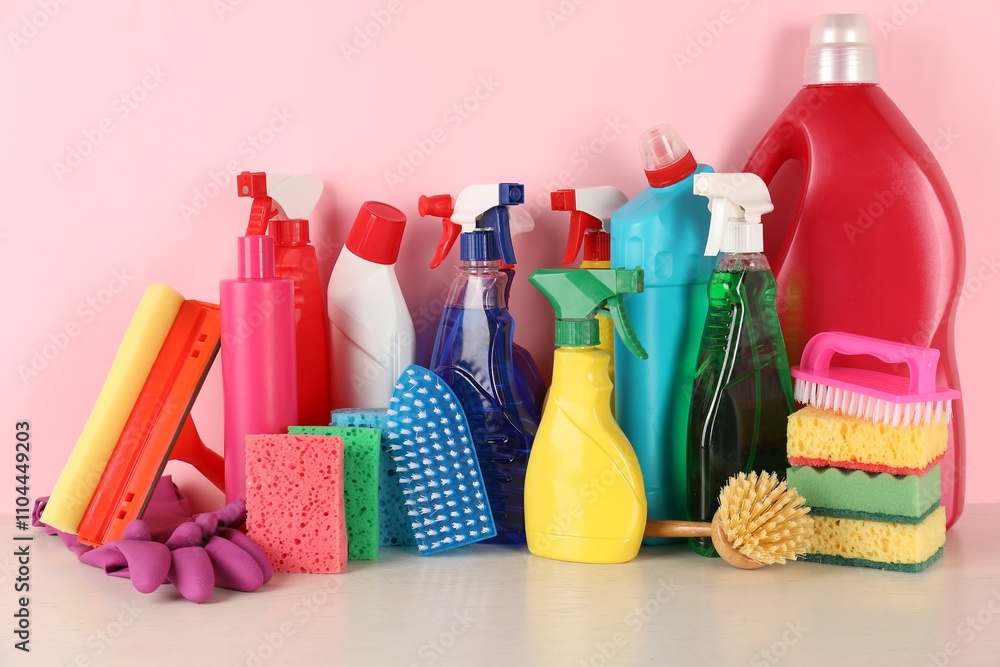 Different cleaning products and supplies on table against pink background Different cleaning products and supplies on table against pink background