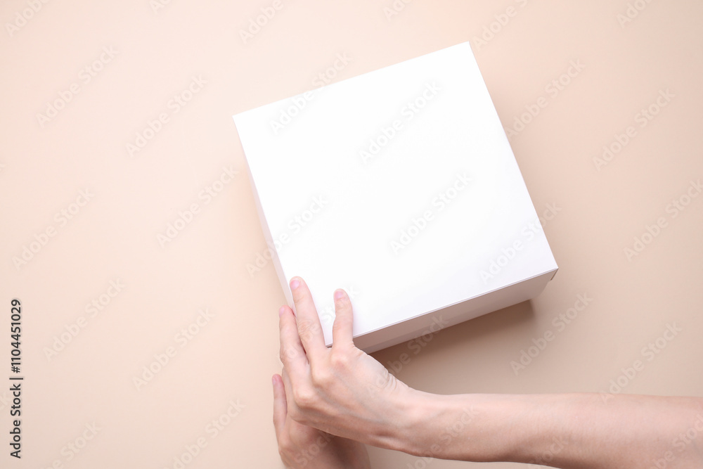 Female hands open white cardboard box on beige background. Mockup for design. Top view Female hands open white cardboard box on beige background. Mockup for design. Top view
