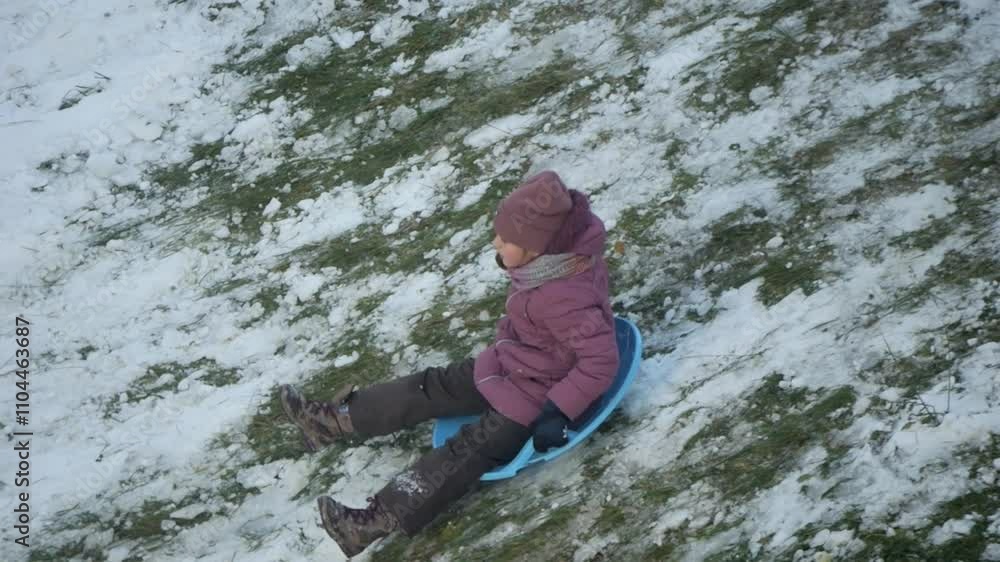 A delightful scene of child sledding joyfully down a snowy hill on a bright winter day A delightful scene of child sledding joyfully down a snowy hill on a bright winter day