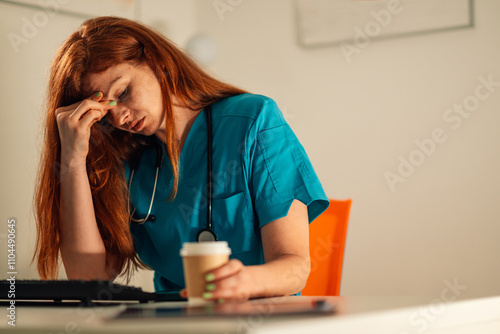 Bilde på lerret Overwhelmed nurse holding coffee at desk in medical workplace