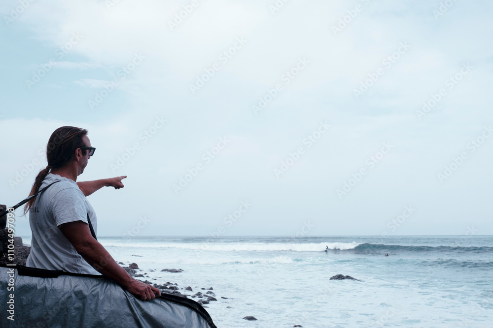 a senior surfer pointing to the waves where he is going to surf.