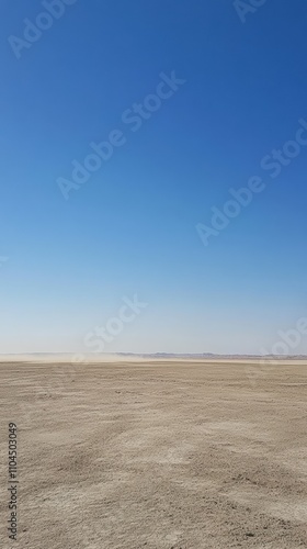 Wind blowing dust across desert landscape under blue sky photo