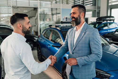 Two men shaking hands in a bright, modern car showroom sealing deal. photo