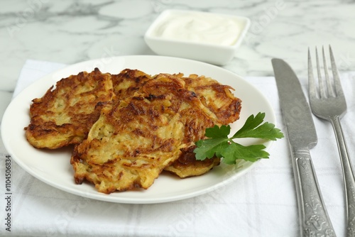 Delicious potato pancakes served on white marble table, closeup photo