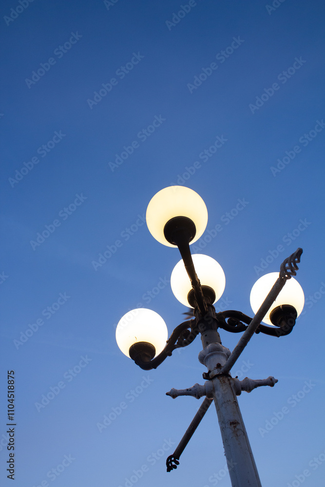 A lantern against a background of clear blue sky with the light on in the evening. A lantern against a background of clear blue sky with the light on in the evening.
