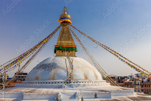 Kathmandu Buddhist stupa Boudhanath. Large spherical stupa in the capital of Nepal UNESCO World Heritage site. Colorful Tibetian prayer flags on the top of stupa with Buddha eyes and blue sky