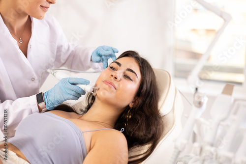 Canvas Print Attractive young girl undergoing radiofrequency skin tightening procedure enhancing facial skin tone and preventing wrinkles