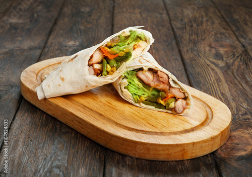 Mexican restaurant fast food - wrapped burritos with chicken and vegetables closeup at wooden desk on table photo