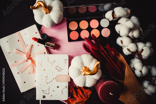 Blush palette, candle, pumpkins, notepad with cotton and dried flowers on a black paper background