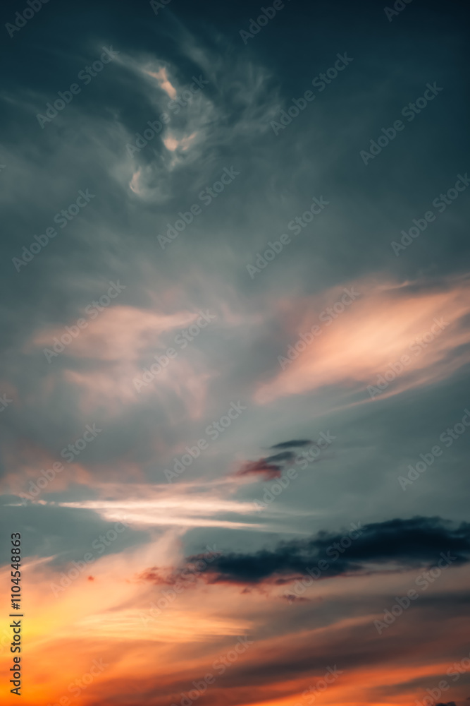 Fototapeta premium Dramatic sunset sky with soft, colorful clouds blending hues of orange, red, and blue. Scenic atmosphere. 