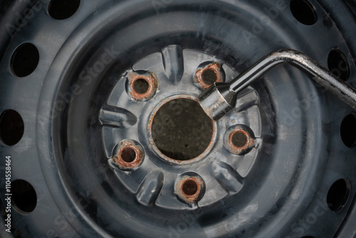 Wheel rim with rusted bolt holes and a wrench: A close-up view of a steel wheel rim showing rust around the bolt holes, with a wrench in action for loosening or tightening.