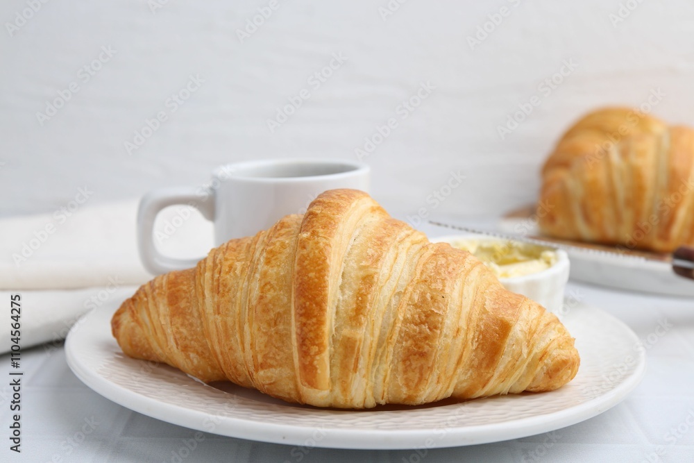 Tasty fresh croissant served on white tiled table, closeup