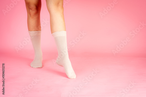 Woman wearing white socks walking on pink background photo